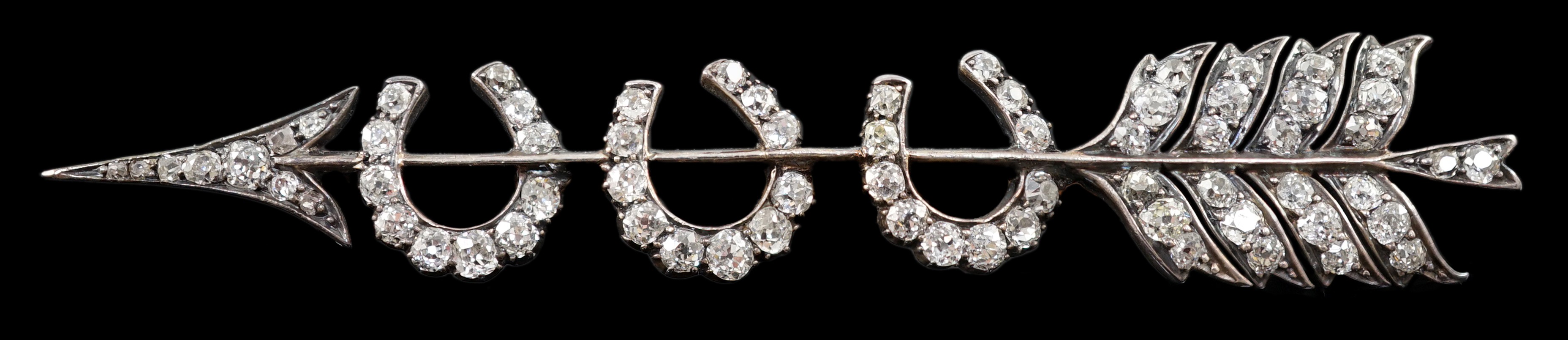 An Edwardian gold, silver and old round cut diamond set gold arrow and triple horseshoe motif set brooch